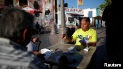 Hombres juegan a las cartas en Mariachi Plaza en el área de Boyle Heights de Los Ángeles, que alberga a muchos inmigrantes mexicanos y centroamericanos.
