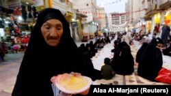 Muslim Irak berkumpul untuk berbuka puasa selama buka puasa bersama di jalan selama bulan suci Ramadhan di Najaf, Irak, 18 April 2021. (Foto: REUTERS/Alaa Al-Marjani)