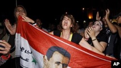 Supporters of Syrian President Bashar al-Assad shout slogans holding their country's flag with a superimposed Assad portrait, Damascus, Syria, August 20, 2011.