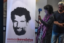ARHIVA - Novinarka pored postera sa likom uhapšenog filantropa Osmana Kavale u Istanbulu, 31. oktobra 2018.