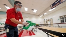 Seorang petugas mendisifektan ruang cafeteria di sebuah di kota Rowlett, Texas menjelang dibukanya kembali sekolah. 