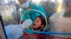 A health worker takes a swab from a Kashmiri boy to test for COVID-19 in Srinagar, Indian-controlled Kashmir, May 8, 2021. Infections have swelled in India since February; more contagious variants and permissive decisions on gatherings are blamed.