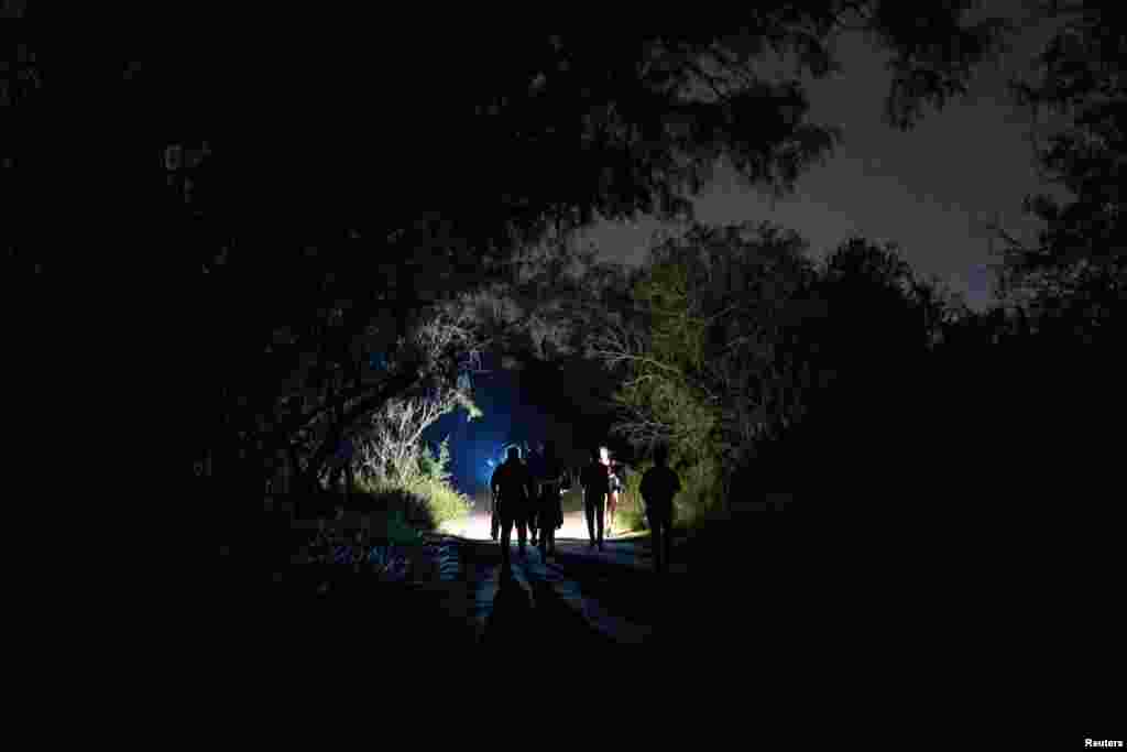 Las familias migrantes solicitantes de asilo caminan mientras son escoltadas a la carretera principal para entregarse a la Patrulla Fronteriza de Estados Unidos.