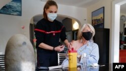 Una paciente recibe una dosis de la vacuna Pfizer-BioNTech Covid-19 por un bombero, en su casa en Les Matelles, sur de Francia, el 19 de marzo de 2021.