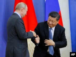 FILE - Chinese President Xi Jinping and Russian President Vladimir Putin shake hands during a ceremony at which Xi was presented with an honorary degree from St. Petersburg State University in St. Petersburg, Russia, June 6, 2019.