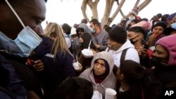 En esta imagen de archivo de febrero de 2021, solicitantes de asilo reciben comida mientras esperan noticias sobre los cambios de la política migratoria estadounidense en la frontera, en Tijuana, México. 