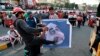 Protesters hit a poster showing Iraqi Prime Minister Adel Abdel-Mahdi with shoes during ongoing anti-government protests in Baghdad, Iraq, Nov. 3, 2019. 