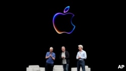 Apple CEO Tim Cook, left, speaks as he is joined by Craig Federighi, right, senior vice president of software engineering, and John Giannandrea, senior vice president of machine learning and AI strategy, during an Apple event in Cupertino, California, June 10, 2024. 