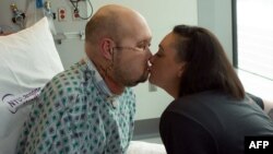 在纽约大学朗格尼健康中心发布的这张未注明日期的照片中，亚伦·詹姆斯在纽约朗格尼健康中心接受第一次全眼和部分面部移植手术后康复期间亲吻他的妻子梅根。 (法新社照片)