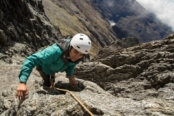In this May 26, 2019 photo, scientist Cherry Andrea Rojas scales rocks during an expedition to the Humbolt glacier, in Merida, Venezuela.