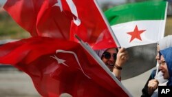 Members of a Turkish pro-government aid group, carrying Syrian and Turkish flags, wait for the departure of trucks carrying humanitarian aid destined for Idlib, Syria, in Istanbul, Sept. 10, 2018. The convoy of 20 vehicles will attempt to reach Syria to deliver basic needs. 