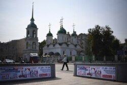 FILE - A woman crosses the road behind election campaign billboards in Moscow, Aug. 27, 2021.