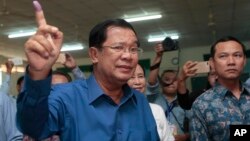 Cambodian Prime Minister Hun Sen of the Cambodian People's Party shows off his inked finger after voting in local elections at Takhmau polling station in Kandal province, southeast of Phnom Penh, Cambodia, Sunday, June 4, 2017. (AP Photo/Heng Sinith)