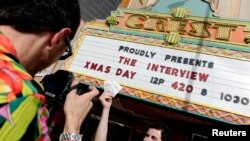 Manager Donald Melancon memamerkan tiket film "The Interview" di depan gedung biodkop Crest Theater di Los Angeles, California (24/12).