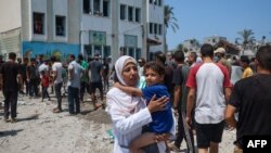 Palestinianos inspeccionam os danos causados por um ataque israelita à escola de Khadija, que alberga pessoas deslocadas em Deir al-Balah, no centro da Faixa de Gaza, a 27 de julho de 2024.