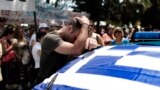 A striking municipal police officer reacts as he leans on a car with a Greek flag during a protest, against new austerity cuts that will affect thousands of public sector workers, in Athens. The government has committed to firing 15,000 people by the end of 2014 and transferring another 12,500 to new positions this year.