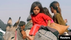 Displaced children from the minority Yazidi sect, fleeing violence from forces loyal to the Islamic State in Sinjar town, ride on a donkey as they head towards the Syrian border, on the outskirts of Sinjar mountain, near the Syrian border town of Elierbeh, Aug. 11, 2014.