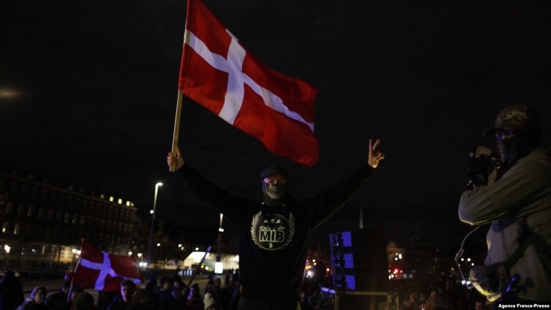 Seorang pengunjuk rasa mengibarkan bendera dalam demo menentang pembatasan terkait pandemi virus corona di Copenhagen, Denmark, 20 November 2021. 