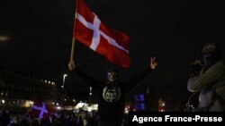 Seorang pengunjuk rasa mengibarkan bendera dalam demo menentang pembatasan terkait pandemi virus corona di Copenhagen, Denmark, 20 November 2021. 