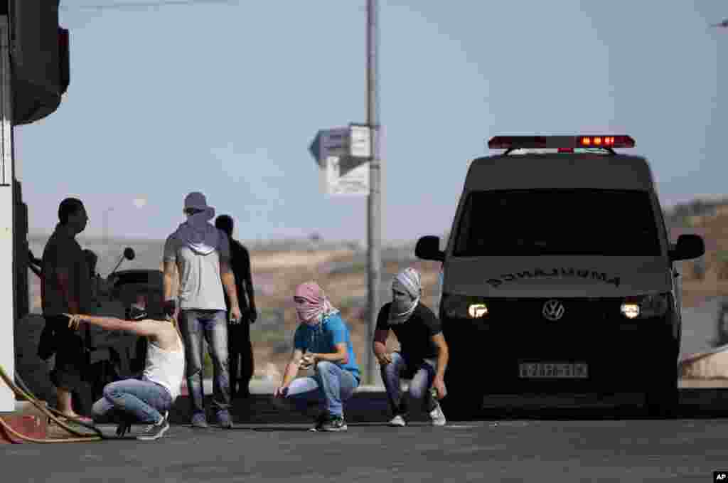 Palestinians take cover during clashes with Israeli soldiers following a protest against the Israeli military action in Gaza, at an area near the Beit El Jewish settlement and the West Bank city of Ramallah, July 25, 2014.&nbsp;