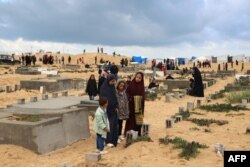 عید الفطر پر رفح کےایک قبرستان میں فلسطینیوں کی قبروں پر ان کے احباب کی ایک تصویر، فوٹو اے ایف پی ۔10 اپریل 2024