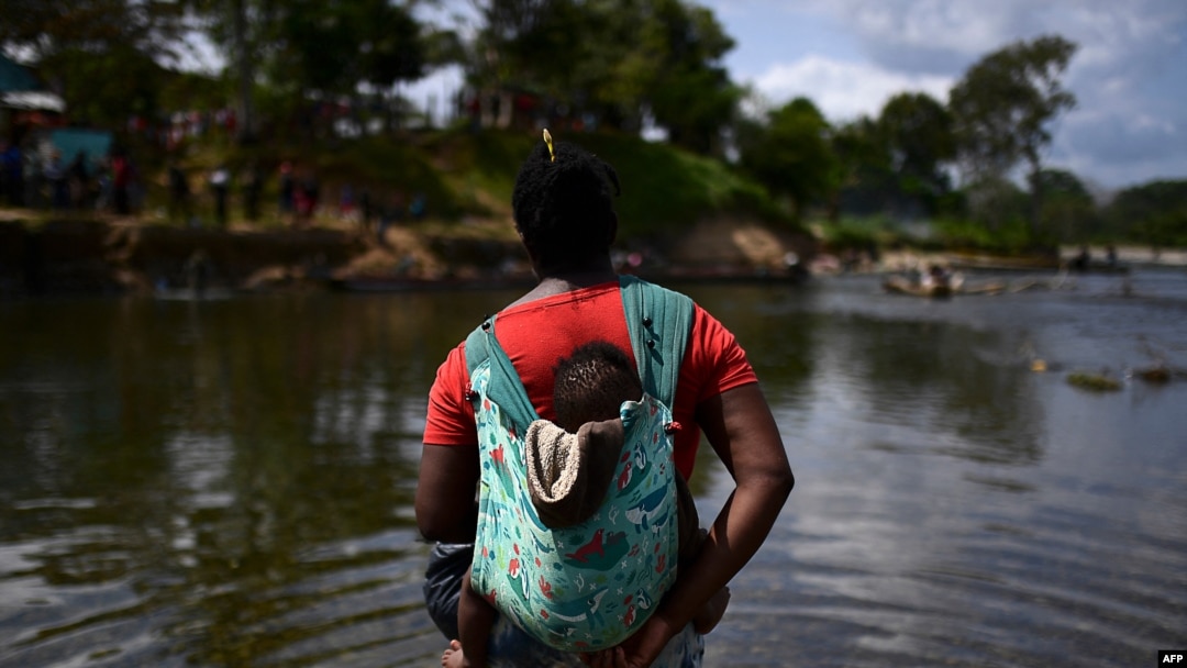 FILE - A migrant carrying a baby crosses the Chucunaque River after walking for five days in the Darien Gap, in Bajo Chiquito village, Darien province, Panama, Feb. 10, 2021.