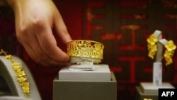 A staff member places gold jewellery in a display at a store in Hangzhou, in China's eastern Zhejiang province on July 27, 2020.