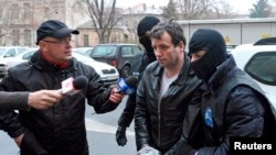 FILE - Marcel Lazar Lehel, 40, is escorted by masked policemen in Bucharest, after being arrested in Arad, west of Bucharest, Romania, Jan. 22, 2014.