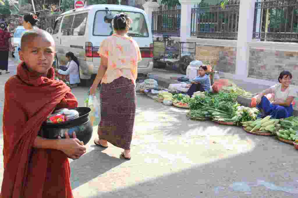 Seorang biksu cilik berjalan di pasar pinggiran jalan di Rangoon (VOA-D.Schearf).