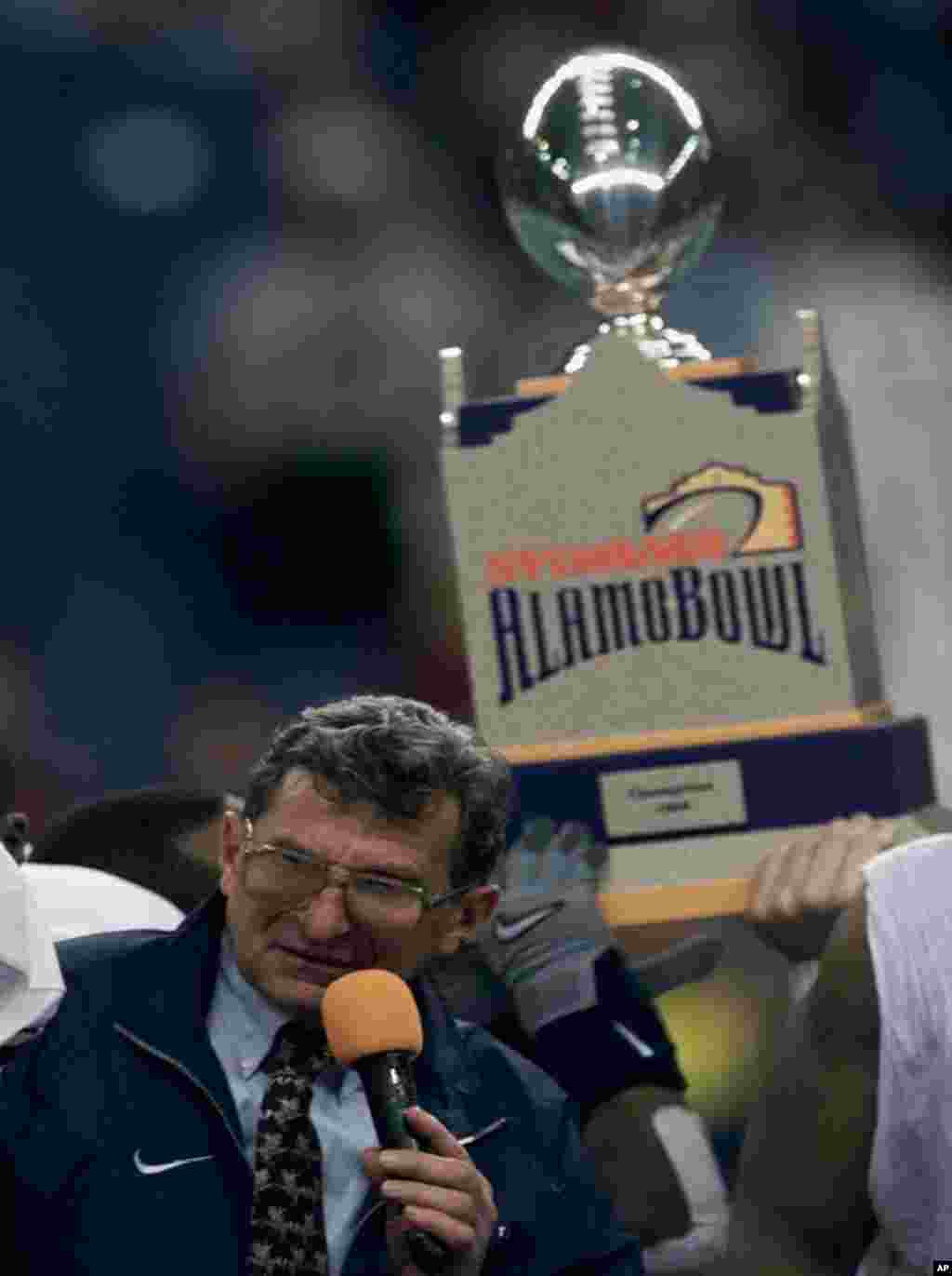Penn State head football coach Joe Paterno calls for assistants to join him after accepting the Alamo Bowl trophy emblematic of their 24-0 victory over Texas A&M, December 28, 1999. (AP)