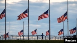 A jogger passes flags flying at half-staff at the Washington Monument on the National Mall following the death of former U.S. President Jimmy Carter, in Washington, Dec. 30, 2024. 