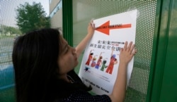 FILE - Ailu Xu, a graduate student from China, posts a sign directing Chinese students to new student orientation at the University of Texas at Dallas in Richardson, Texas, Aug. 22, 2015.