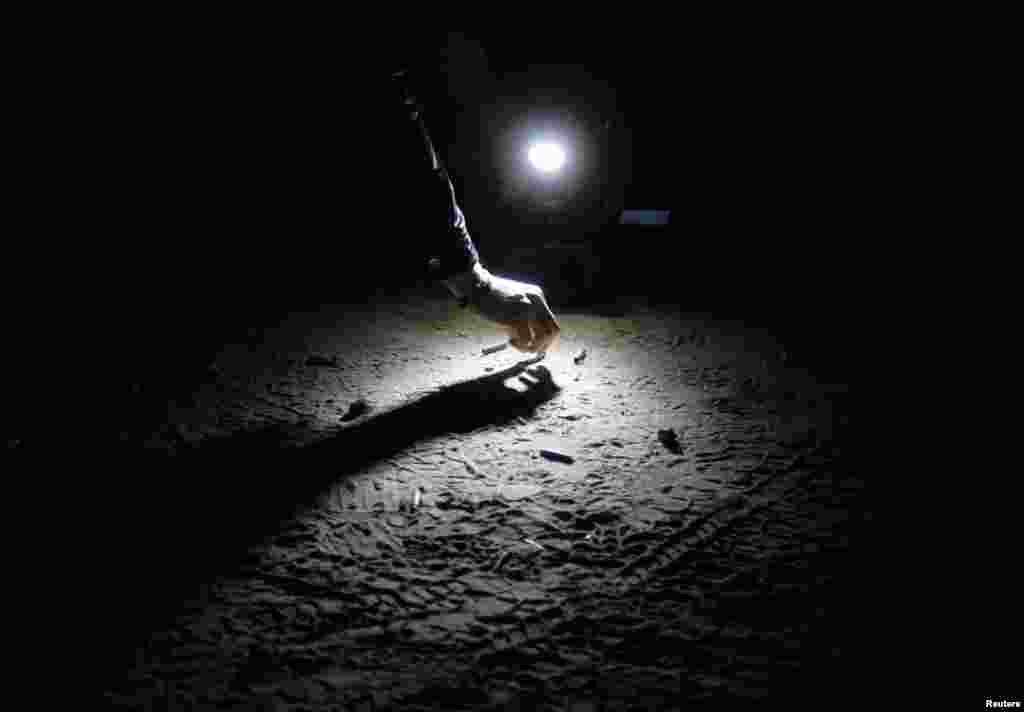 A forensic investigator inspect bullet shells at a crime scene after a shooting at Ameca town outside Guadalajara, Mexico, January 12, 2013.