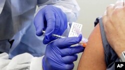 FILE - In this March 16, 2020, file photo, Neal Browning receives a shot in the first-stage safety study clinical trial of a potential vaccine for COVID-19, the disease caused by the new coronavirus, at the Kaiser Permanente Washington Health…