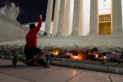 A man kneels in front of a memorial of candles and flowers outside the Supreme Court, Sept. 18, 2020, in Washington, after the Supreme Court announced that Justice Ruth Bader Ginsburg has died of metastatic pancreatic cancer.
