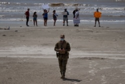 A police officer walks away from local residents protesting closed beaches on the 4th of July amid the coronavirus pandemic, in Galveston, Texas, July 4, 2020.