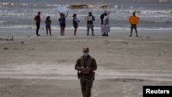 A police officer walks away from local residents protesting closed beaches on the 4th of July amid the global outbreak of the coronavirus disease (COVID-19) in Galveston, Texas, July 4, 2020. 