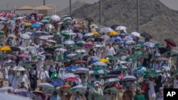 Umat muslim menggunakan payung untuk melindungi diri dari sinar matahari di Mina, dekat kota suci Mekkah, Arab Saudi, Selasa, Juni 18 Agustus 2024. (Foto: AP)