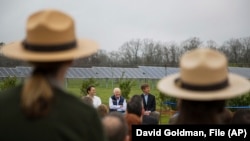 FILE - Former President Jimmy Carter, center, sits with his grandson Jason Carter, left, and George Mori, executive vice president at SolAmerica Energy during a ceremony for a solar panel project on Jimmy Carter's farmland in Plains, Ga., Feb. 8, 2017.