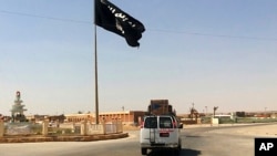 En esta imagen de archivo tomada el 22 de julio de 2022 muestra un vehículo al momento de pasar junto a una bandera del grupo Estado Islámico en el centro de Rawah, una ciudad a 281 kms (175 millas) al noroeste de Bagdad.