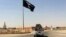En esta imagen de archivo tomada el 22 de julio de 2022 muestra un vehículo al momento de pasar junto a una bandera del grupo Estado Islámico en el centro de Rawah, una ciudad a 281 kms (175 millas) al noroeste de Bagdad.