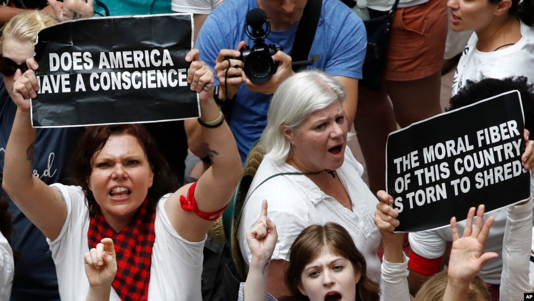 Para perempuan mengacungkan spanduk pada saat berunjuk rasa memprotes pemisahan keluarga imigran ilegal, di luar Gedung Kantor Senat di Washington DC, 28 Juni 2018.