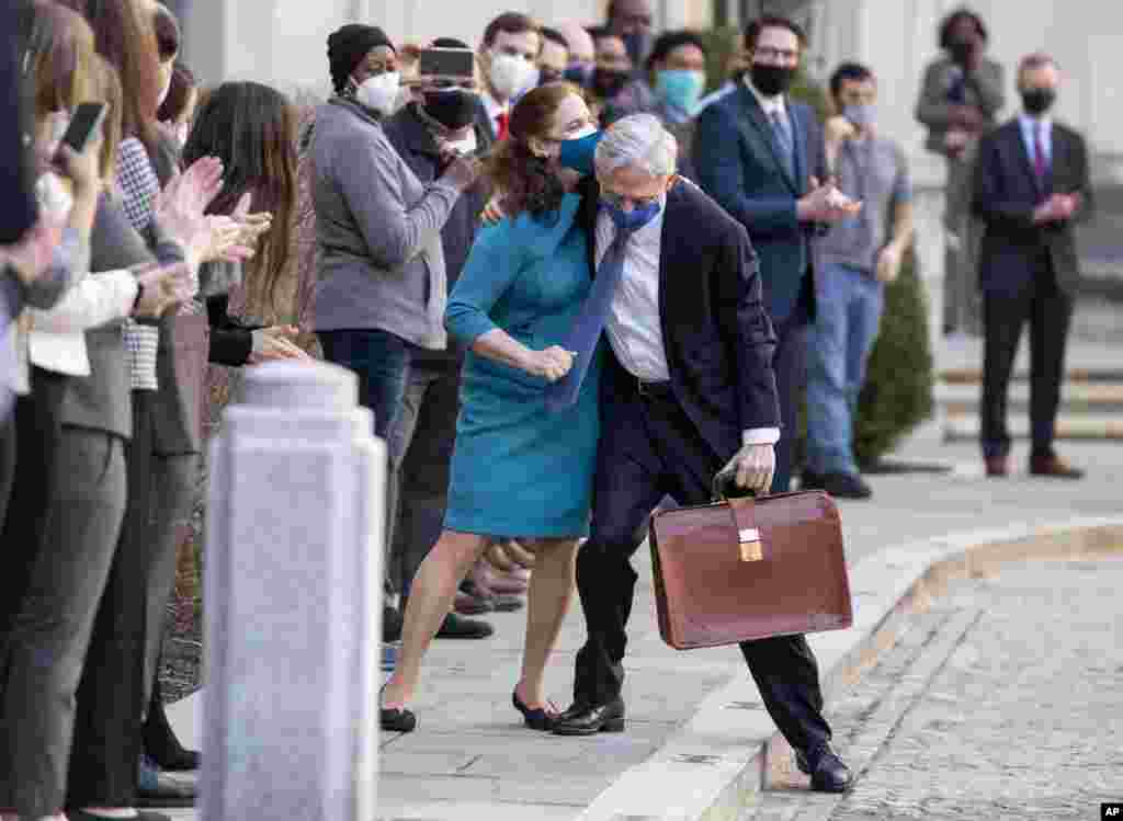 President Joe Biden&#39;s pick for attorney general Merrick Garland hugs his wife Lynn as he arrives for his first day at the Department of Justice in Washington, D.C.