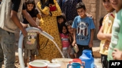 FILE - Residents fill up buckets with water from cisterns provided by humanitarian organisations during water shortages in Syria's northeastern city of Hasakah, Aug. 22, 2020.