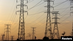 FILE: A man walks beneath electricity pylons of South Africa utility Eskom, in Orlando, Soweto, South Africa. Taken Jan. 16, 2023. Uganda has decided to take back two hydro plants that Eskom has run since 2002. 