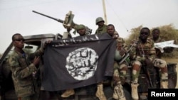 Des soldats nigérians tiennent un drapeau Boko Haram saisi dans la ville a récemment repris de Damasak, Nigeria, 18 mars 2015 