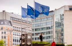FILE - European Union flags flap in the wind outside of EU headquarters in Brussels, Sept. 11, 2019.