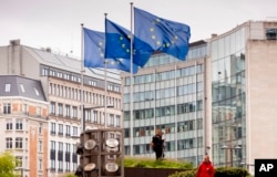 FILE - European Union flags fly as gardeners work on the outside of EU headquarters in Brussels, Sept. 11, 2019.