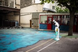 A worker sprays a gel on the ground to absorb lead during a decontamination operation at Saint Benoit school near Notre-Dame cathedral in Paris, Aug. 8, 2019.