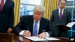 Presiden AS Donald Trump saat menandatangani instruksi untuk menarik Amerika dari perjanjian perdagangan Pasifik, TPP, Januari 2017. (AP/Evan Vucci)